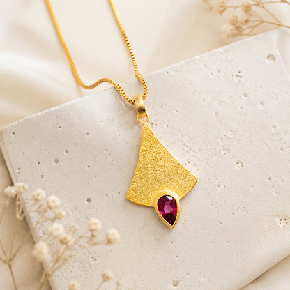 Pendentif en or avec pierre précieuse rose.